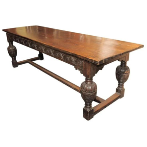 Antique Jacobean style wood dining table with carved details.
